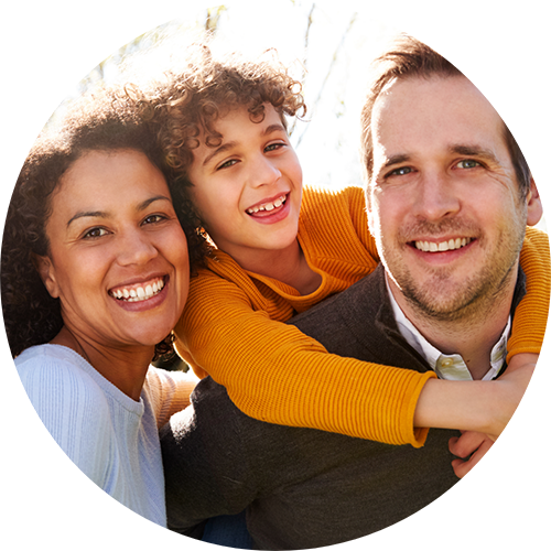 Family of three smiling in the sunlight