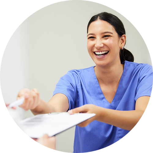 Smiling dental team member handing a clipboard to a patient